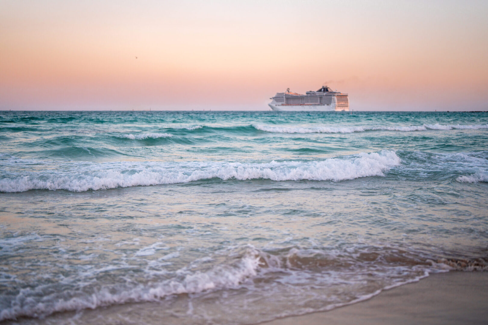 Cruise ship on ocean at sunset.